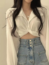 A white satin twisted front long sleeve shirt with sleeves tied at the front for a stylish look