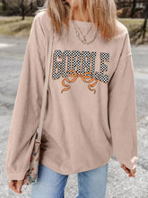 Beige corduroy long sleeve top with black and white checkered gobble graphic and orange ribbon made of slightly stretchy material machine wash cold