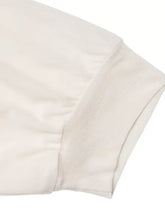 Cream-colored two tone long sleeve bodysuit with soft textured fabric and ribbed cuffs for elegant comfort