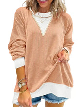 Two-tone ribbed knit sweatshirt in soft peach with white v-neckline, cuffs, hem, and exposed seam detail, slightly stretchy