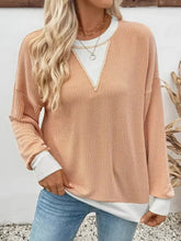 A slightly stretchy peach ribbed knit sweatshirt with exposed seam detailing and contrasting white v-neck and cuffs