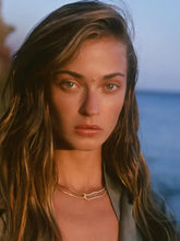 Woman with wavy brown hair wearing gold-plated stainless steel necklace