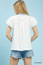 Off-white short-sleeved blouse with blue trim featuring an abstract applique split neck design by Umgee