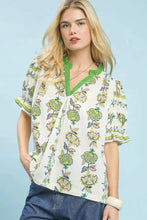 White blouse with vibrant green and yellow floral abstract border print featuring ruffled sleeves and lace collar