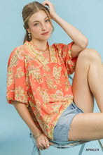 A flowing coral-colored umgee apricot floral boho blouse with paisley print and ruffled short sleeves