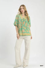 Umgee apricot floral mint green blouse with yellow and peach floral print, short flutter sleeves, and v-neckline