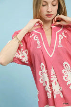 Pink women’s tunic with white embroidered floral boho print, short sleeve, and split neck v-neckline by Umgee