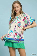 Cream-colored umgee border print puff sleeve blouse with vibrant paisley floral patterns on lightweight fabric