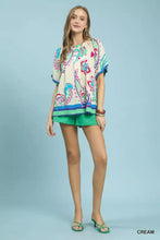 Cream-colored umgee border print puff sleeve blouse with vibrant blue green and pink paisley pattern