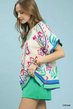Umgee cream blouse with vibrant floral border print puff sleeves in pink blue green and purple with a relaxed fit