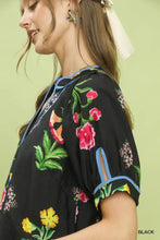 Black umgee blouse featuring vibrant botanical print contrast with pink yellow green blossoms and blue contrast trim button