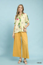 Cream-colored umgee botanical print short-sleeve blouse with green contrast trim perfect for casual wear