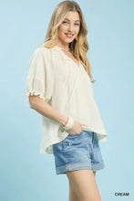 Cream-colored umgee cotton gauze ruffle top with lightweight fabric, ruffled sleeves, and beaded neckline detailing