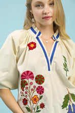 Cream-colored umgee embroidered floral v-neck blouse with vibrant red pink green and orange embroidery along neckline and front