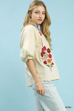 Cream-colored umgee embroidered floral v-neck blouse with vibrant pink red and orange floral embroidery on front
