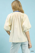 Cream-colored embroidered floral v-neck blouse with puffed sleeves and blue collar trim from umgee