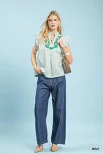 A taupe leather crossbody bag with structured rectangular shape and stitching complements umgee embroidered ruffle sleeve top