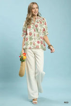 A woman wears an umgee floral button-front short sleeve cream blouse with pink green embroidery and white pants