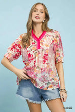Umgee floral contrast pleat neck top with vibrant pink and red blossoms and bright fuchsia ruffled neckline trim on light background