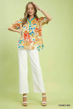 A vibrant umgee floral print blouse in honey mix tones with contrast pleat neck and short flutter sleeves