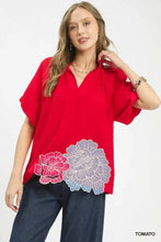 Red short-sleeved umgee blouse with floral embroidered hem featuring pink and purple flower motif design