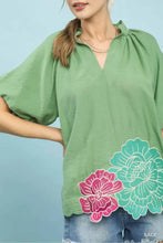 Umgee floral embroidered hem blouse in green with pink and teal blossoms featuring floral embroidered hem detail