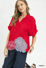 Red blouse with puff sleeves featuring floral embroidered hem in pink and lavender by umgee