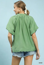 Sage-colored umgee loose-fitting blouse with short flutter sleeves and a floral embroidered hem detail