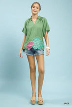 Sage green Umgee short-sleeved blouse with floral embroidered hem design on the front for stylish wear