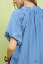 A soft cerulean blue umgee blouse with ruffled neckline puffed sleeves and a lightweight floral embroidered hem