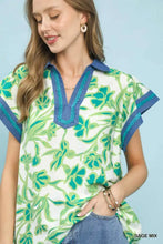 Women’s short-sleeved umgee floral split neck top in sage mix with vibrant green floral patterns and blue trim accents
