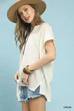 Umgee flowy cream-colored short sleeve blouse with v-neck, loose fit, and asymmetrical hemline for casual wear
