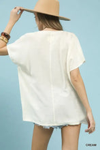 Cream-colored umgee flowy v-neck short sleeve blouse shown from the back with loose fit and visible seam detail