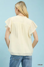 Cream-colored umgee flutter sleeve blouse with delicate ruffled sleeves and scalloped hemline trim detail