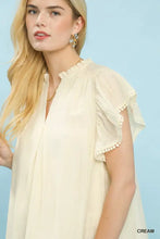 Cream-colored lightweight umgee flutter sleeve blouse with ruffled pom-pom trim and soft gathered neckline
