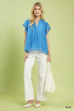 A vibrant blue flutter sleeve relaxed blouse with v-neckline and delicate ruffled trim detail by umgee