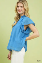A vibrant blue lightweight umgee flutter sleeve relaxed top with ruffled cap sleeves and delicate pom-pom trim