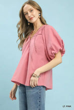 A soft pink umgee lace inset puff sleeve blouse with delicate lace detailing along the neckline