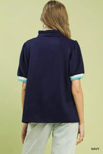 Navy blue short-sleeved blouse with ruffled collar and light teal contrast trim in luxe knit fabric from Umgee Luxe