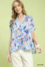 A women’s short-sleeved umgee mix boho printed blouse in blue with tropical foliage and striped collar and cuffs