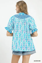 A woman wears an intricate blue and white mix boho puff sleeve blouse with ruffled cuffs and embroidered collar