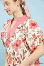 Woman wearing an Umgee Mix floral puff sleeve blouse in coral and cream with a pink striped collar floral print blouse