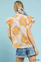 A woman wears an Umgee honey mix floral ruffle sleeve blouse with ruffled short sleeves and off-the-shoulder design