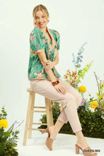 A woman wears a teal and peach floral print umgee mixed abstract puff sleeve blouse with short puffed sleeves