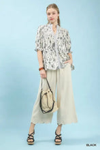 Beige woven bucket bag with black drawstring and handles complementing the umgee mixed print button front top