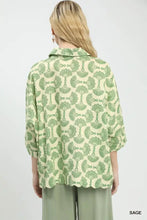 A woman wearing an umgee sage green and cream printed button down shirt with an intricate fan shaped pattern
