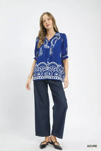 A vibrant royal blue umgee printed puff sleeve split neck top with white paisley embroidery and puffed sleeves paired with navy trousers