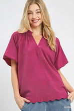A berry-colored umgee scalloped hem textured blouse with short sleeves and a v-neck design