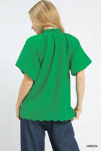 A vibrant green umgee scalloped hem textured blouse with short sleeves and ruffled neckline for casual wear