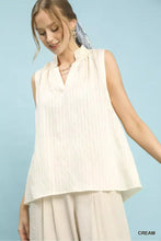 Cream-colored sleeveless textured notch neck top with ruffled neckline and vertical pleats by umgee